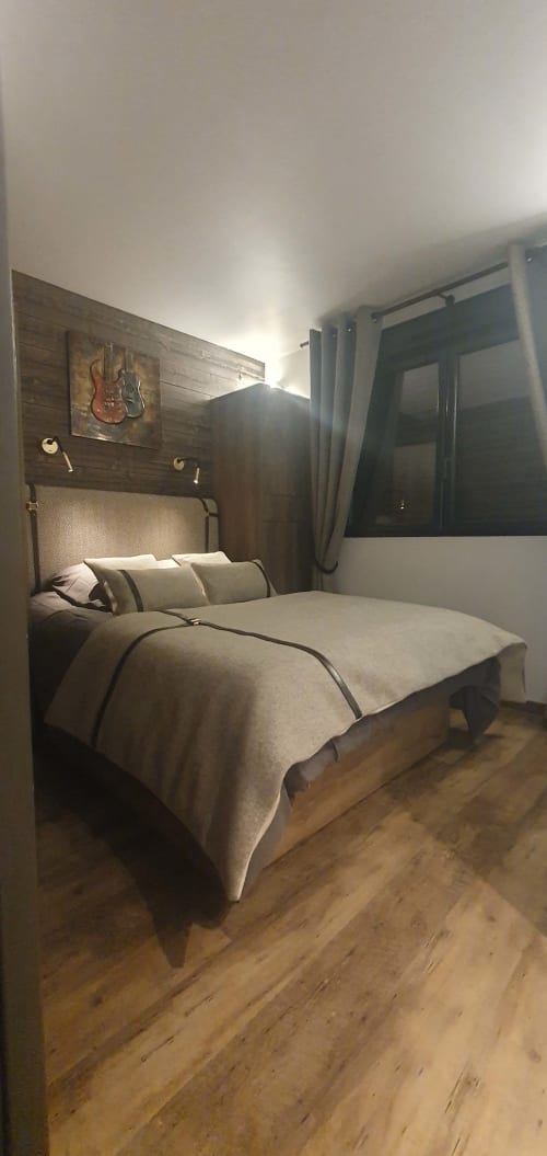 Chambre moderne à la Résidence Le Pacha à Courchevel avec lit, mur en bois, art guitare et vue sur les montagnes