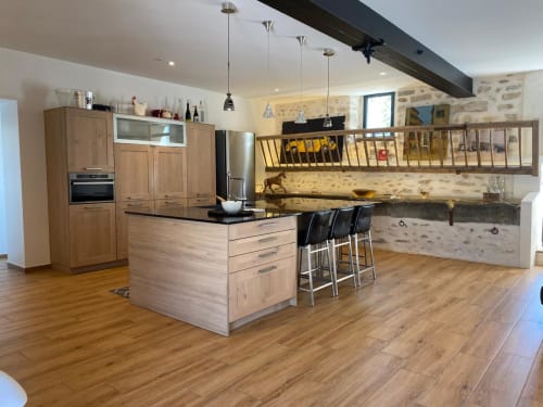 Cuisine moderne avec mobilier en bois, coin repas au comptoir et murs en pierre rustique au gîte La Ferme du Châtaignier près de Paris