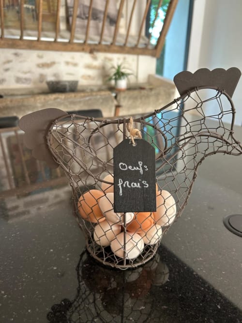Panier en métal pour œufs avec étiquette ardoise « Oeufs frais » sur comptoir sombre, La Ferme du Châtaignier