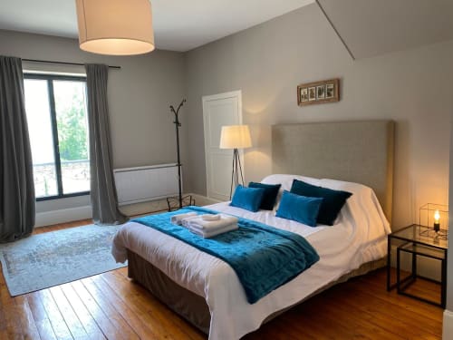 Elegant bedroom at La Ferme du Châtaignier gîte with blue velvet bedding, neutral walls, and parquet flooring near Paris
