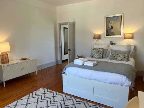 Elegant bedroom at La Ferme du Châtaignier gîte in Essonne with white bed, modern décor, and wooden floors