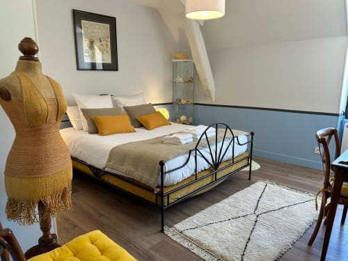 Elegant bedroom at La Ferme du Châtaignier gîte with iron bed frame, golden accents, and modern decor in Essonne near Paris