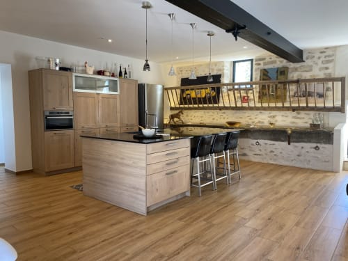 Cuisine moderne avec meubles en bois, îlot, et murs en pierre rustique au gîte La Ferme du Châtaignier près de Paris