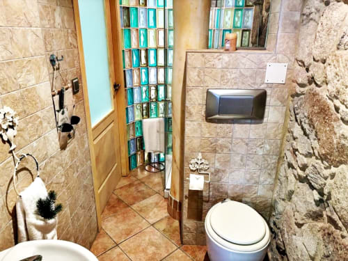 Baño moderno del apartamento boutique Solpor en Baiona con paredes alicatadas, inodoro, ducha y ventana de bloques de vidrio