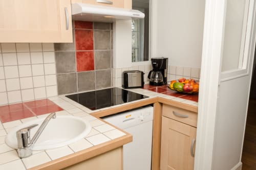 Cuisine moderne de l'Apartement Liberté à Villa République Normandie, Caen, avec dosseret en carrelage rouge et gris, inox