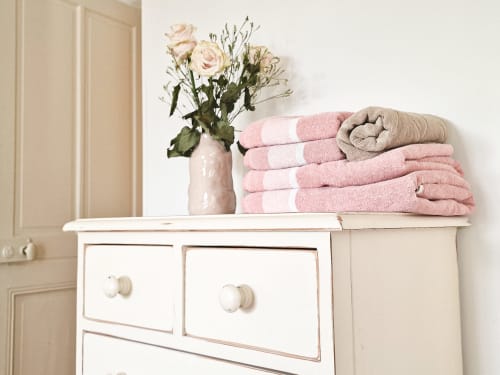 Élégante commode blanche avec serviettes rayées rose et roses à Villa République Normandie, Caen