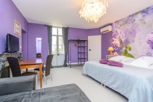 Suite violette avec un meuble de rangement pour vêtements climatisation et TV avec audiodescription.