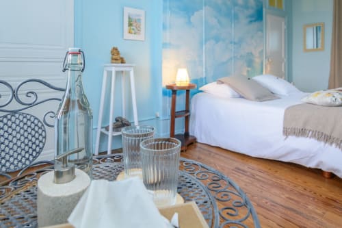 Table avec deux chaise dans la chambre et mise à disposition d'une bouteille d'eau filtrée avec verres.