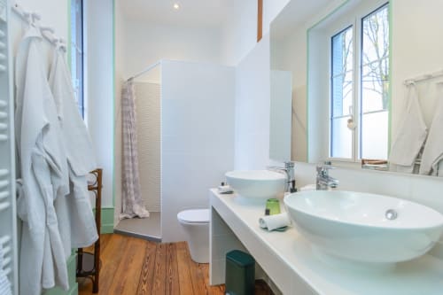 Salle de bain attenante à la chambre avec deux vasques, verres à dents, petites serviettes d'invités et petites serviettes. WC dans la salle de bain
