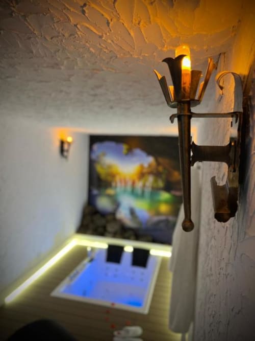 Romantic cave suite with torch sconce, jacuzzi tub, and scenic landscape artwork at Retiro del Teatro