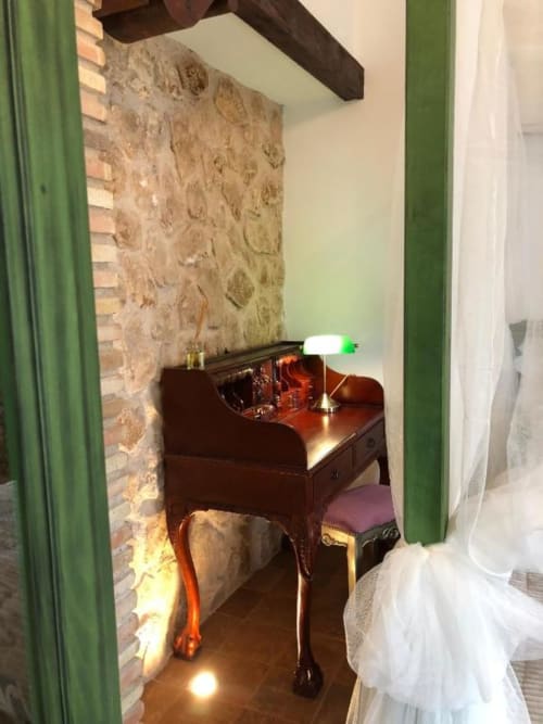 Cozy desk area in Retiro del Teatro room with dark wood furniture, lamp, and exposed brick wall in Almagro, Ciudad Real
