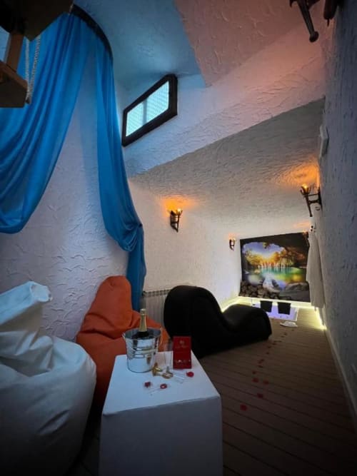 Romantic cave suite with blue canopy, red chair, ambient lighting, TV, and jacuzzi at Retiro del Teatro, Almagro