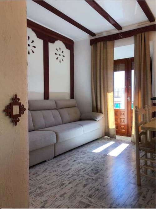 Modern studio bedroom with gray sofa bed, dark wood beams, and terrace access in Almagro, Ciudad Real