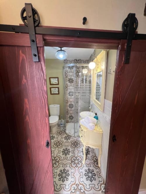 Baño moderno en Suite Deluxe del Complejo Turístico Retiro del Teatro, Almagro con puertas abatibles y azulejos estampados