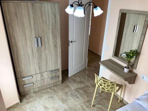 Dormitorio moderno en Complejo Turístico Retiro del Teatro en Almagro con guardarropa de madera, tocador, silla amarilla y piso de baldosas