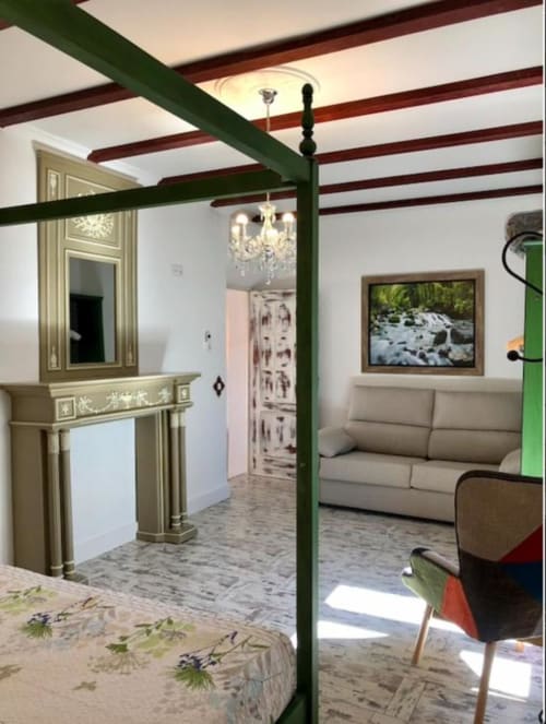 Corral de Comedias Studio bedroom with green canopy bed, beamed ceiling, fireplace, and living area at Retiro del Teatro,