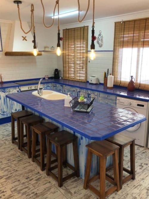 Modern kitchen with blue tile countertop, wooden bar stools, and pendant lighting in Corral de Comedias Studio, Almagro