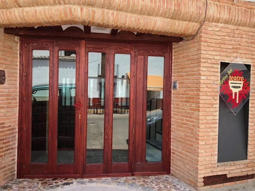 Puertas de patio de madera roja con paneles de vidrio que se abren al patio interior del Complejo Turístico Retiro del Teatro, Almagro