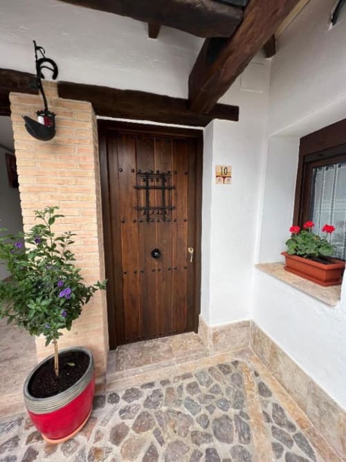 Entrada a la Suite Deluxe 10 en Complejo Turístico Retiro del Teatro, Almagro con puerta de madera y decoración rústica de patio.