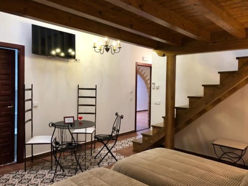 Family room in Spanish hotel with wrought iron furniture, dining table, stairs, and wood beams