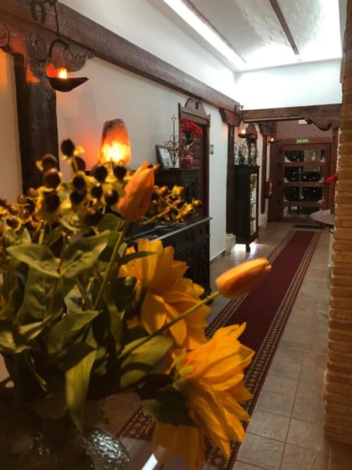 Bright hallway at Complejo Turístico Retiro del Teatro with yellow flowers, warm lighting, and rustic wooden beams