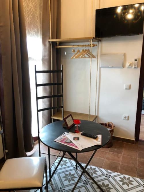 Modern hotel room in Almagro with round black desk, wall-mounted TV, wardrobe, and wooden ladder shelf