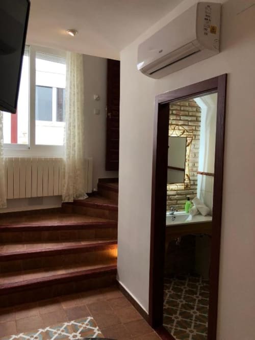 Modern hotel room hallway with wooden stairs, air conditioning unit, mirror, and doorway at Complejo Turístico Retiro del