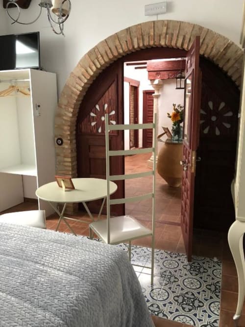 Retiro del Teatro bedroom with arched brick doorway, white round table, and traditional Spanish courtyard view in Almagro