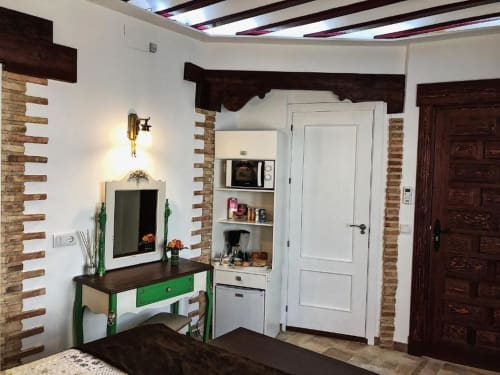 Suite B bedroom at Complejo Turístico Retiro del Teatro with green desk, brick accents, white door, and flat-screen TV in