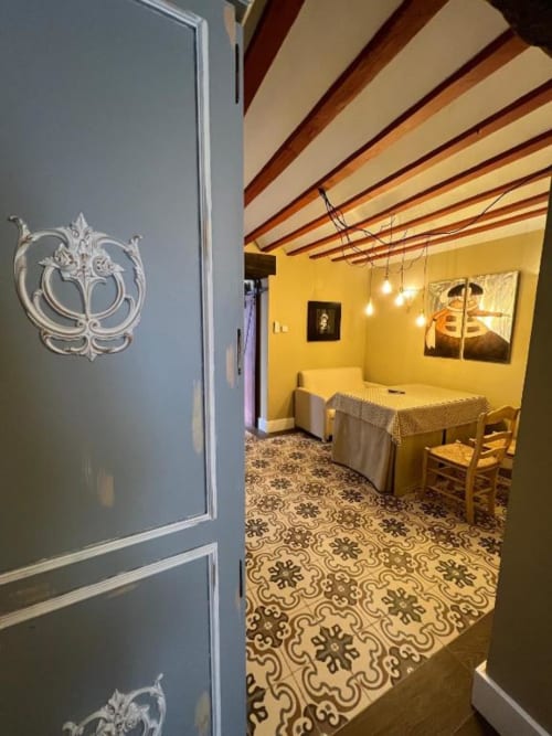 Acceso a la Suite Deluxe 10 del Complejo Turístico Retiro del Teatro, con paredes amarillas, vigas expuestas y motivos decorativos