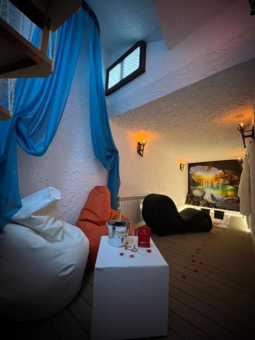 Romantic cave suite with blue drapes, white bean bags, red tantra chair, and jacuzzi at Retiro del Teatro in Almagro