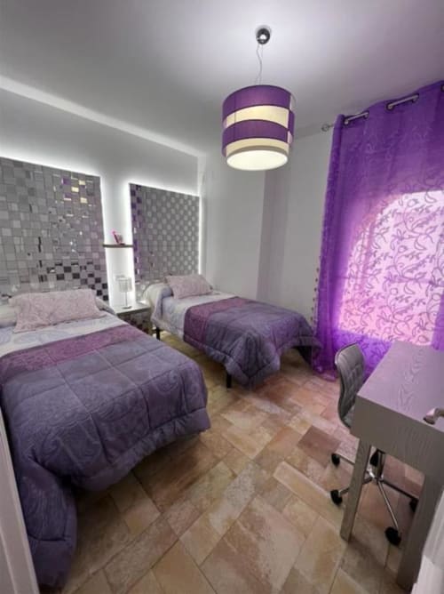 Purple-themed bedroom at Complejo Turístico Retiro del Teatro in Almagro with twin beds, modern pendant light, and city