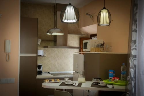 Cocina y comedor modernos en apartamento de Almagro con luces colgantes y distribución compacta