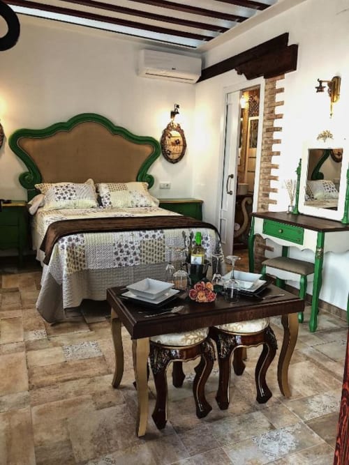 Elegant Suite B bedroom at Complejo Turístico Retiro del Teatro with green headboard, dark wood furniture, and brick accents