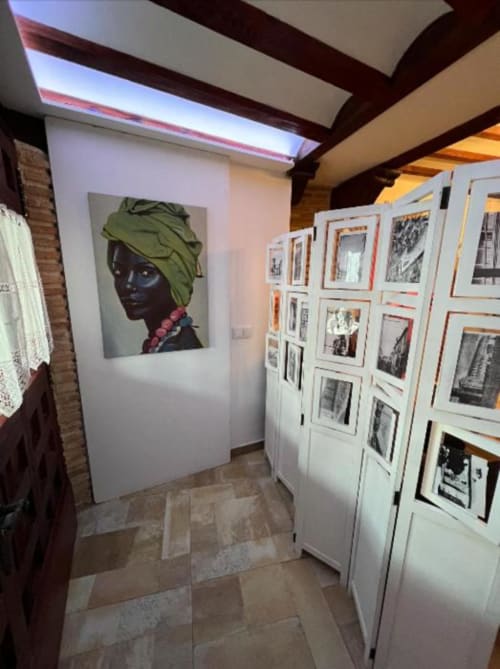 Art gallery interior in Almagro hotel with portrait painting and framed photographs on white walls