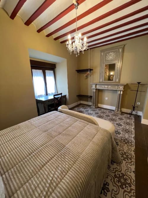 Suite Deluxe en Complejo Turístico Retiro del Teatro con cama, lámpara de araña, chimenea y techo con vigas en Almagro