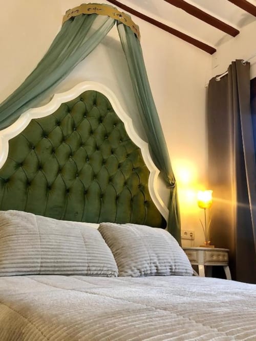 Elegant bedroom with tufted green headboard, sheer sage canopy, white bedding, and city views at Complejo Turístico Retiro