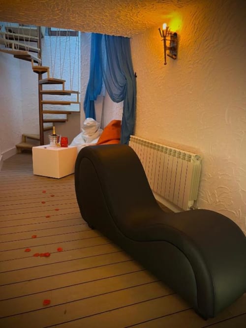 Modern romantic suite interior with black sculptural chair, spiral staircase, and warm golden lighting at Retiro del Teatro