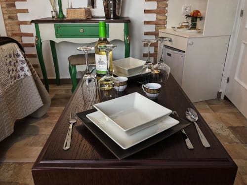 Elegant dining table setting at Suite B, Retiro del Teatro, Almagro with white plates, wine glasses, and green desk backdrop.