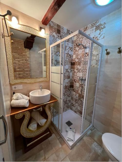 Modern bathroom in Almagro with round sink, patterned shower enclosure, and wooden vanity at Retiro del Teatro