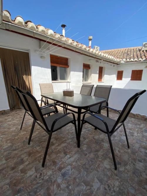 Terraza exterior con mesa y sillas de comedor en Complejo Turístico Retiro del Teatro en Almagro, estilo español de paredes blancas