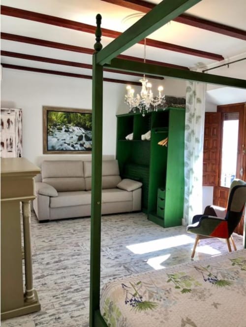 Green canopy bed studio in Almagro hotel with beamed ceiling, cream sofa, and natural light