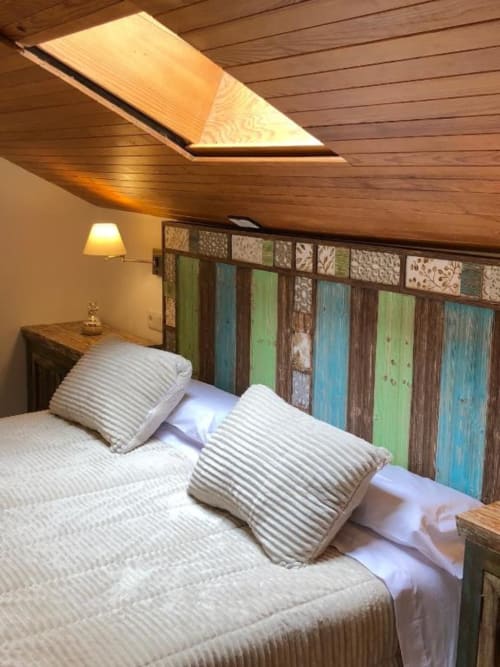 Cozy attic bedroom with wooden ceiling, two beds, and colorful headboard at Retiro del Teatro in Almagro
