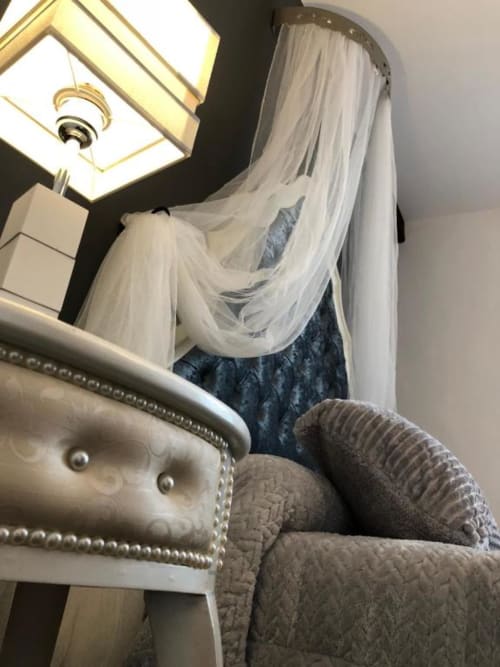 Guest sitting on upholstered chair with sheer white canopy drape in Blue Romance room at Retiro del Teatro, Almagro