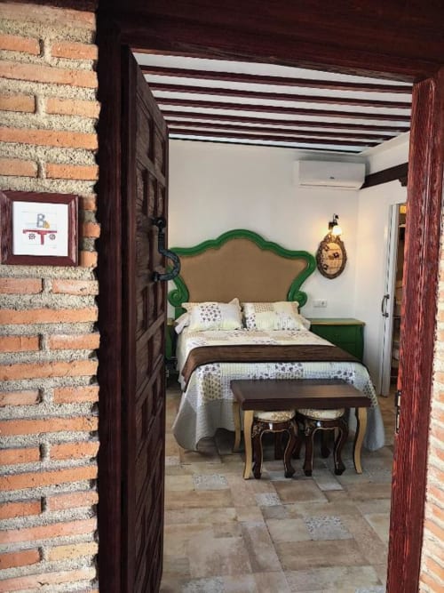 Suite B bedroom at Complejo Turístico Retiro del Teatro in Almagro, Spain with green headboard and wooden beams