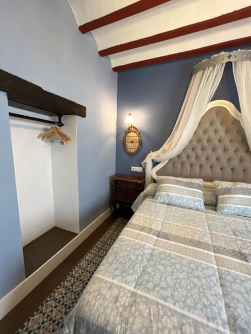 Deluxe Suite at Complejo Turístico Retiro del Teatro with elegant bed, draped canopy, exposed beams, and blue accent wall in