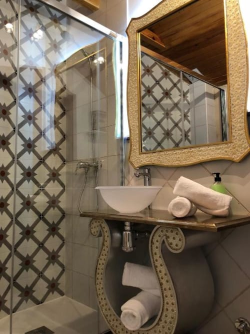 Elegant bathroom in Romantic Room 4 at Retiro del Teatro with patterned tiles, vessel sink, and ornate mirror