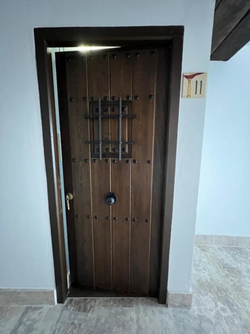 Dark wooden door with metal studs and decorative ironwork in Complejo Turístico Retiro del Teatro, Almagro