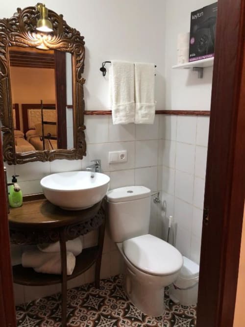 Elegant bathroom at Complejo Turístico Retiro del Teatro with round white sink, toilet, ornate mirror, and tiled flooring