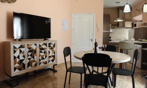 Sala de estar moderna con comedor, TV en mueble geométrico y cocina abierta en hotel Almagro